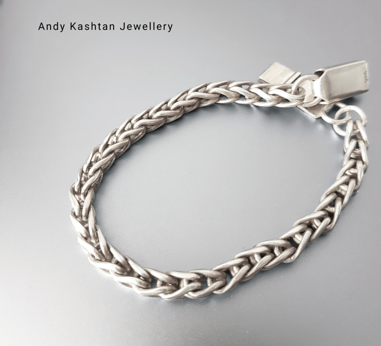 Handmade sterling silver braided chain bracelet by Andy Kashtan Jewellery on a metallic background.