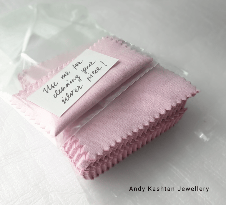 Pink jewelry cleaning cloths for silver pieces, individually packaged with a 'Use me for cleaning your silver piece!' note