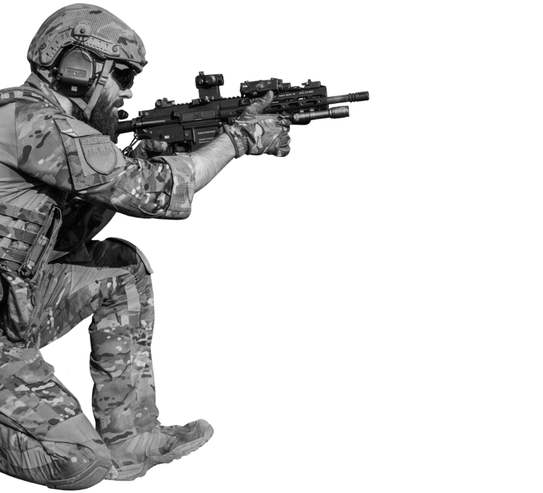 Profesionalus airsofto žaidėjas su pilna taktine ekipuote klūpi ir taikosi su moderniu šratasvydžio 