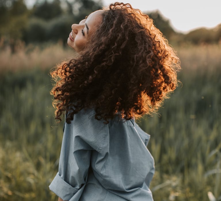 curly gurl laughing in the meadow looking up