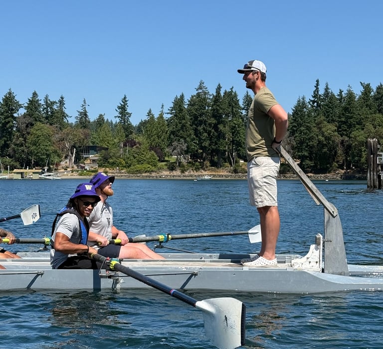 Team rowing on the water with a coach guiding them during a leadership and team-building event