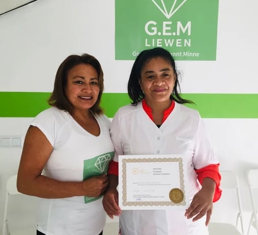 Deux femmes souriantes posant dans un centre de formation G.E.M. Liewen, l’une tenant un certificat