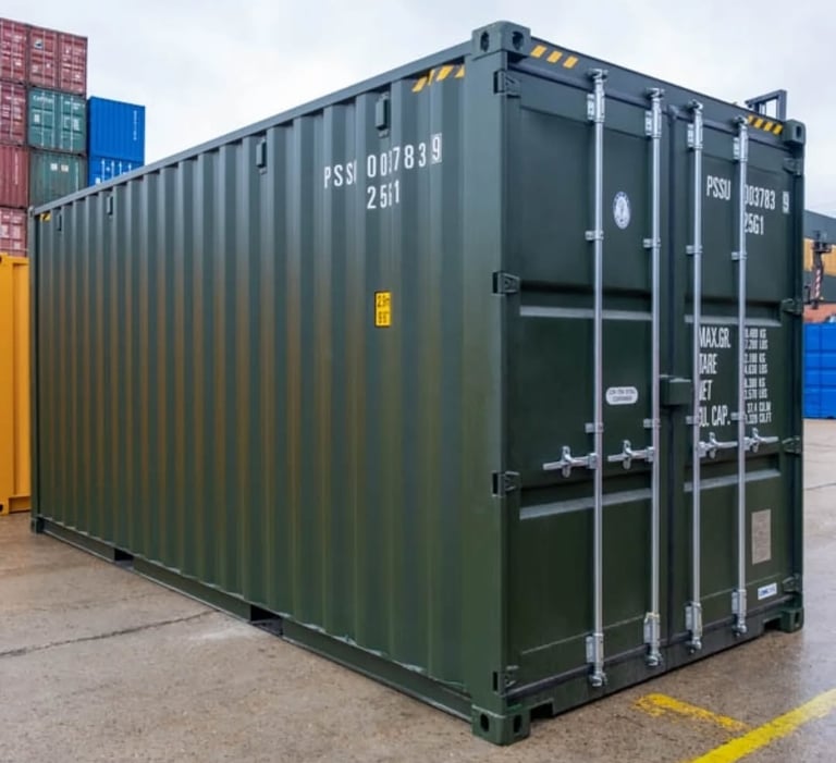 Dark green industrial steel shipping container for storage and cargo transport at a shipyard.