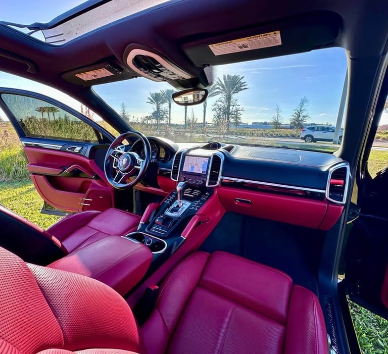 Interior of a luxury SUV with red leather seats and black trim, freshly detailed and parked under clear Florida skies
