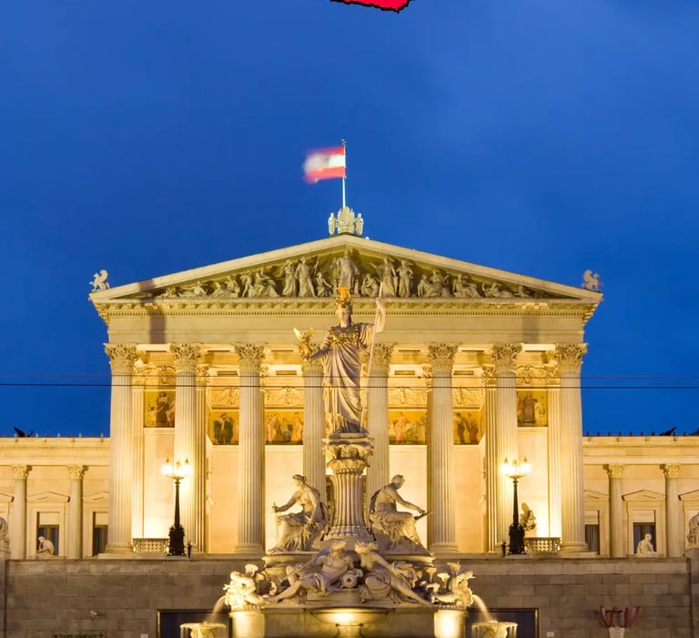 Vienna Parliament building lit up at night with Austrian flag and Athena fountain
