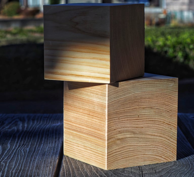 Two stacked cypress wood blocks showing natural grain patterns on a rustic timber surface.