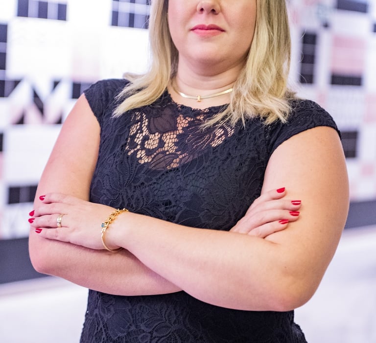 uma mulher loira de meia idade com vestido preto e esmalte vermelho nas unhas.