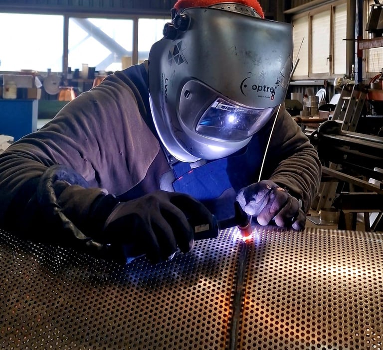 a man in a welding helmet welding a piece of metal