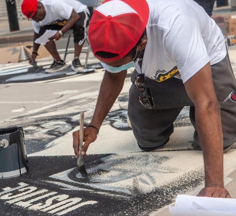 An image of two artists working on a justice mural.