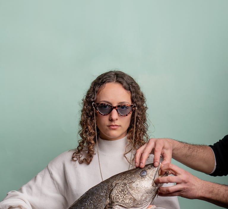 fotografía corporativa de gastronomia de una mujer sosteniendo un pez con gafas de sol