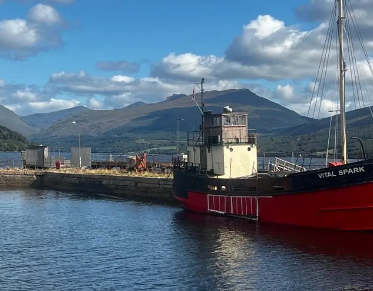 a boat docked at a pier with hills in the background