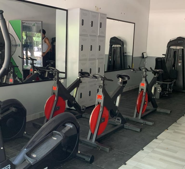 A modern gym interior featuring stationary bikes, elliptical machines, and storage lockers for fitness training.
