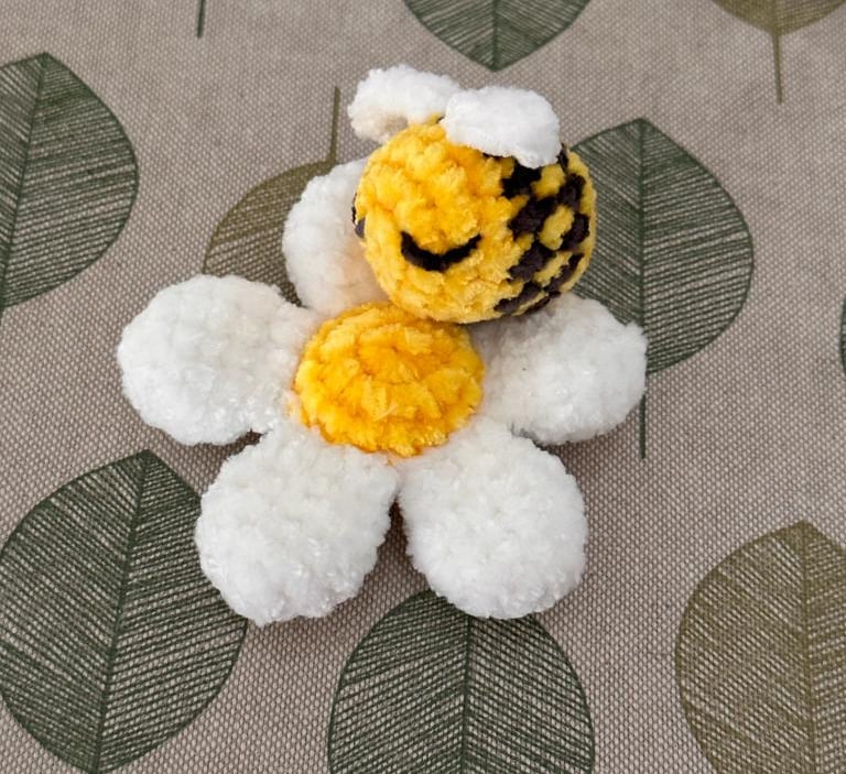a handmade amigurumi stuffed daisy with bee toy 