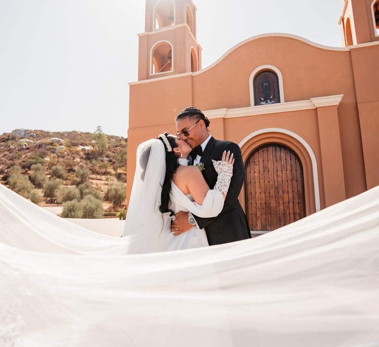 a bride and groom kissing in front of a church