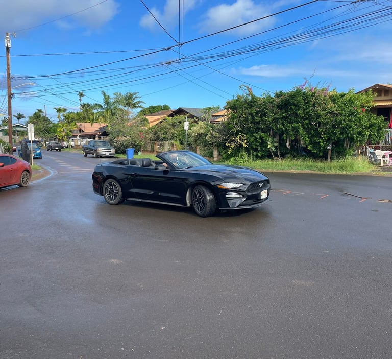 a car driving down a street with cars parked on the side of the road