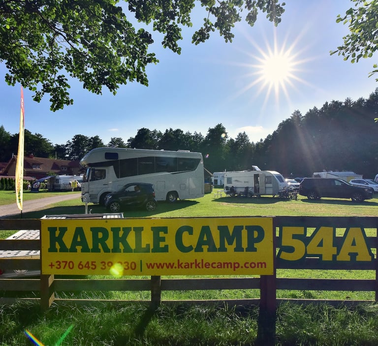 Sunny motorhome and caravan campsite at Karkle Camp under a bright blue sky.
