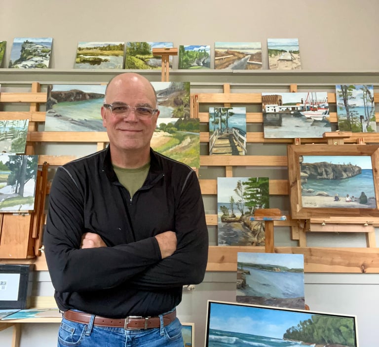 Gary McCaslin standing in front of a wall of paintings