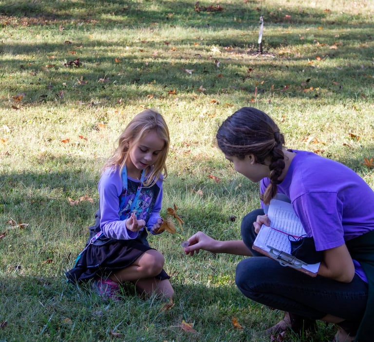 Teacher with one of our youth students outside, picking up natural pieces for an art project.
