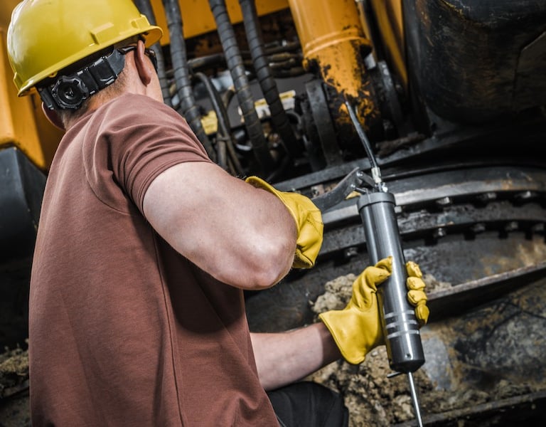 A man greasing his equipment using Grease Dispensers to properly Lubricate his machineries