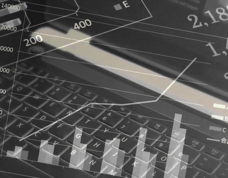 Dados financeiros digitais e gráficos de análise de negócios sobrepostos ao teclado de um laptop.