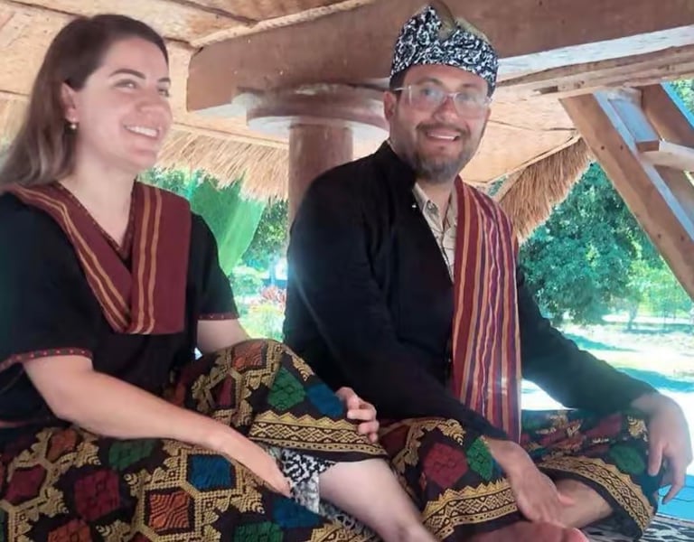 a man and woman sitting on a couch using Tradisional Suku Sasak clothes
