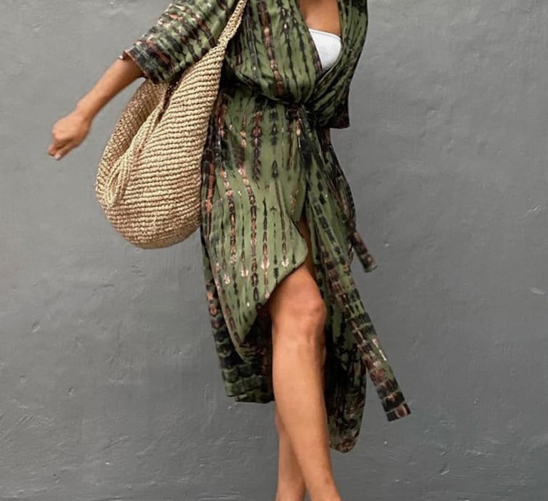 Woman wearing a white croptop underneath a green swuimsuit cover, which is worn as a wrap dress.