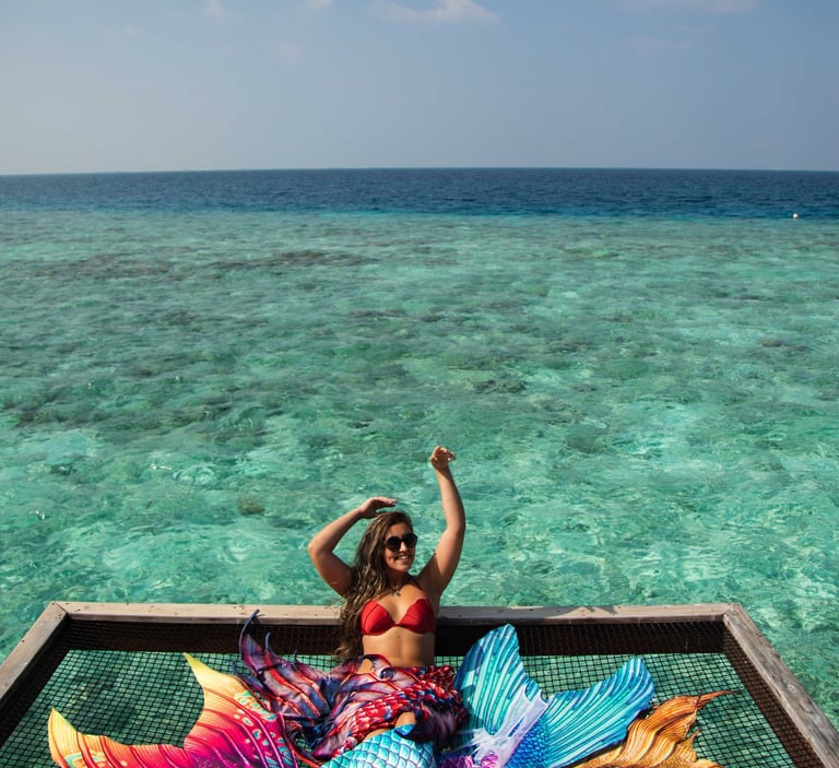 Seriea Guardia sitting on a lounge-net above the water, surrounded by her tails.