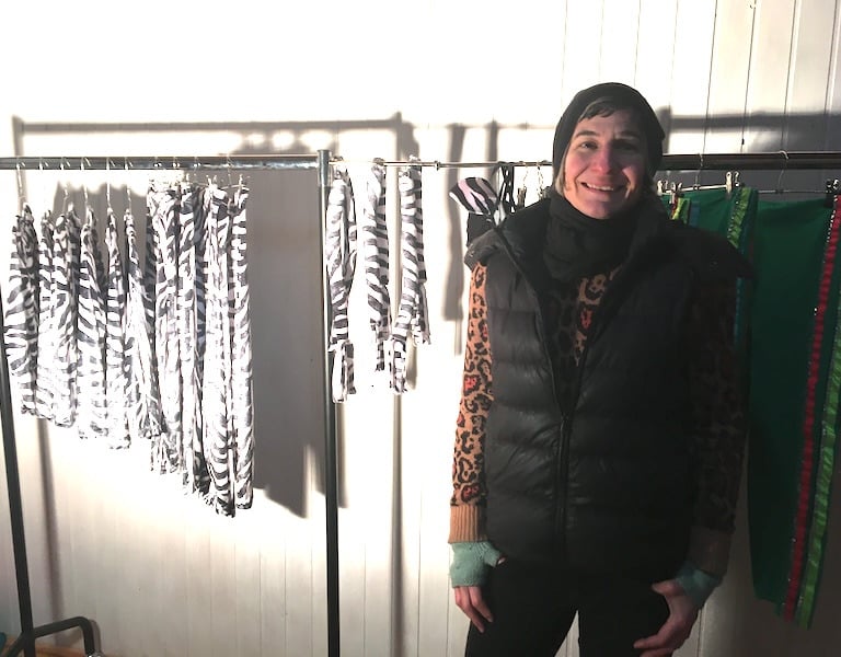 samuko standing next to a clothing rack of zebra print costumes..