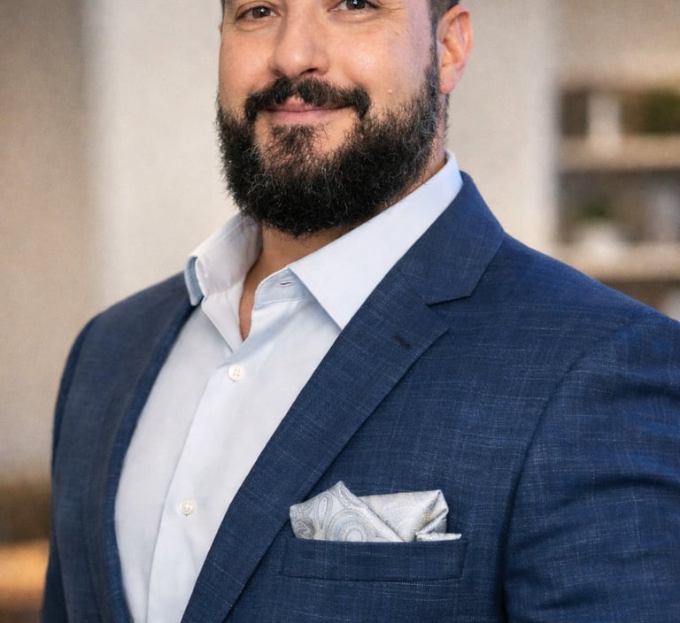 Professional man with a beard wearing a blue suit jacket and pocket square for a corporate headshot.
