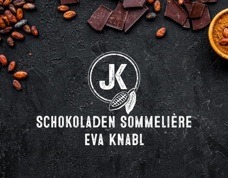 Schokoladen Sommelière Eva Knabl logo on dark stone background with cocoa beans and dark chocolate pieces.