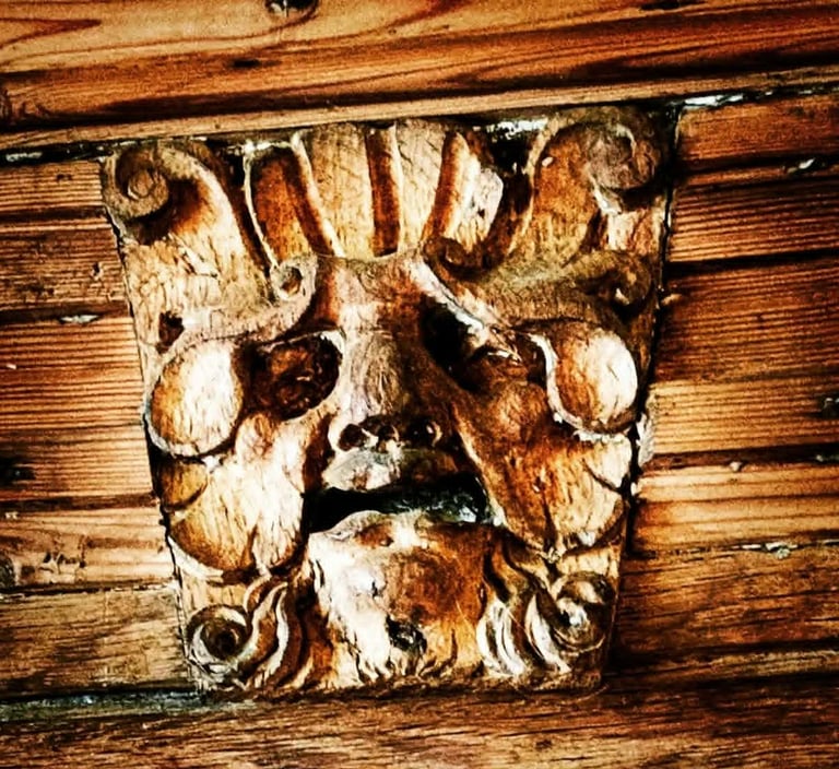 an old carving of a Green Man face in wood