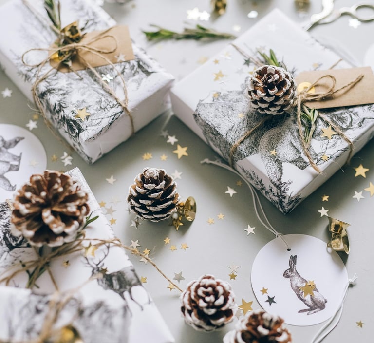 Beautifully wrapped Christmas presents with kraft paper, red ribbons, and pine springs.