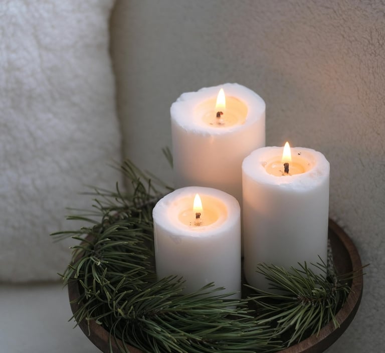 Christmas candles in a wooden tray surrounded by pine branches, creating a warm festive glow