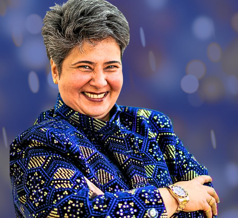 Indian woman with short hair smiling at camera. She is wearing a navy blue jacket with gold spots