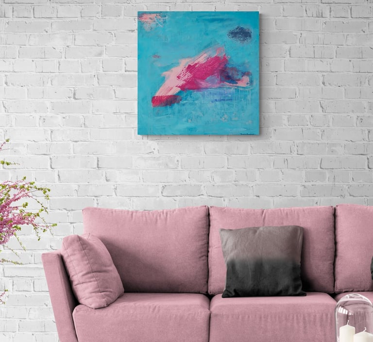 Blue and pink painting on white brick wall above pink sofa