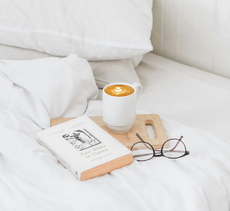 a cup of coffee and a book on a bed