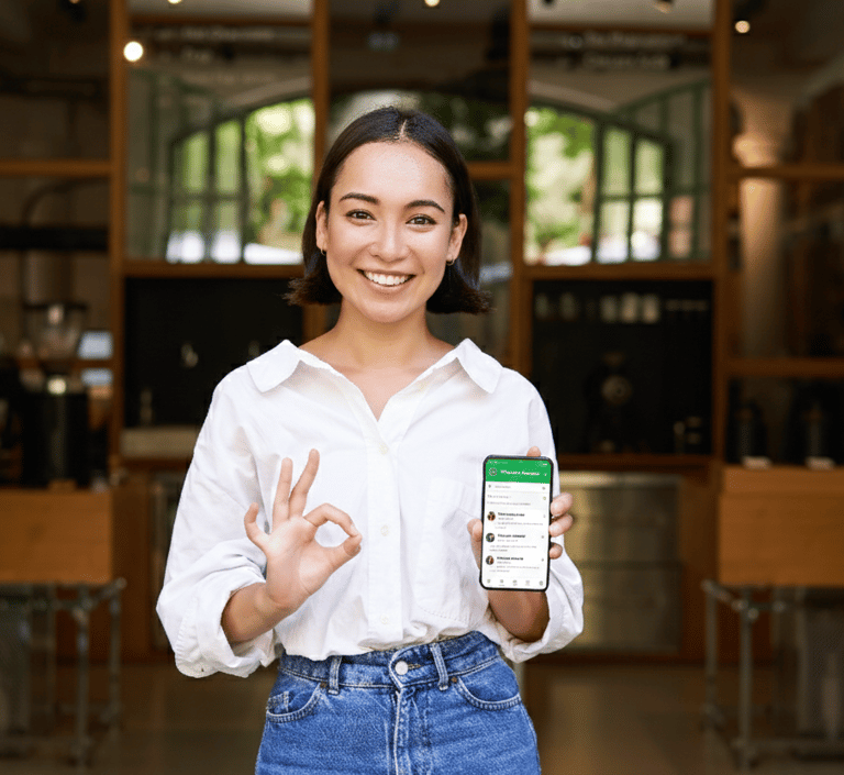 Mujer sosteniendo celular con la aplicación Whatsapp Business abierta.
