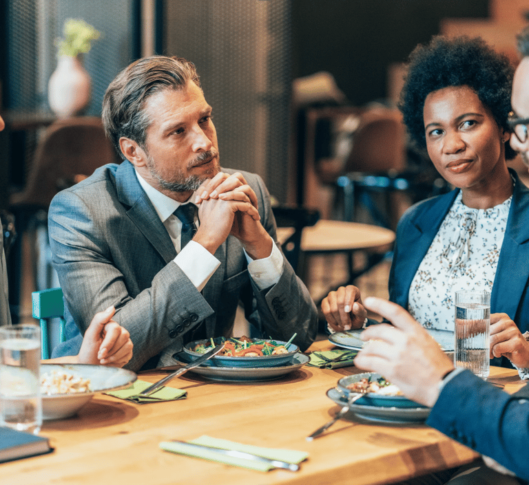 a group of people sitting at a table with food
