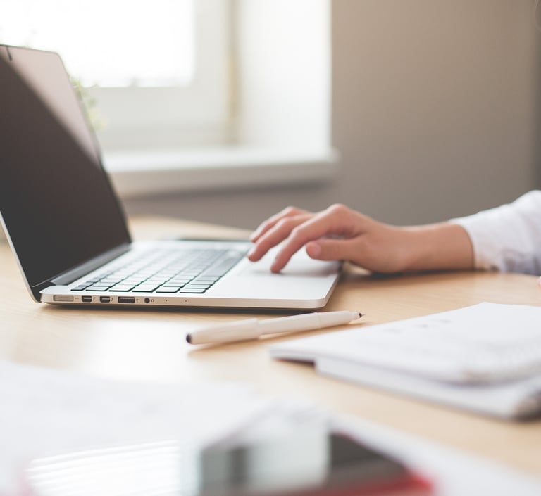 a woman sitting at a desk with a laptop and a notebook