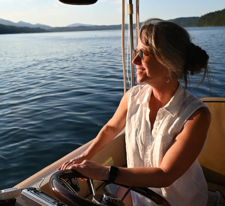 a beautiful woman in a white shirt is sitting on a eco-friendly electric boat cruising hood canal