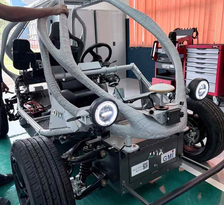 Custom-built autonomous electric vehicle prototype with sensors and roll cage in a workshop environment.