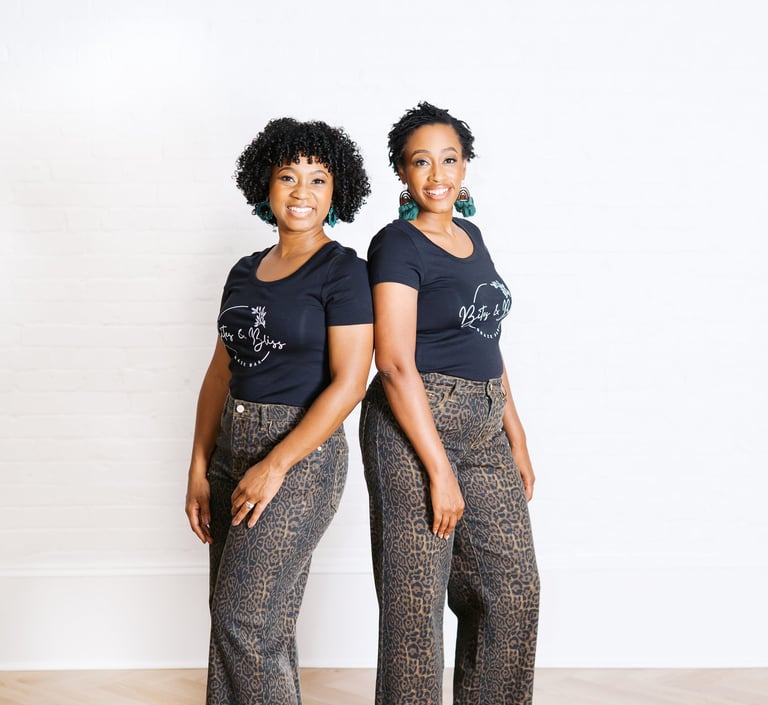 two women standing next to each other in front of a white wall