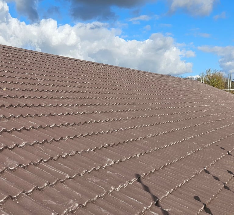 A clean, newly installed brown concrete tile roof under a blue sky with white clouds.
