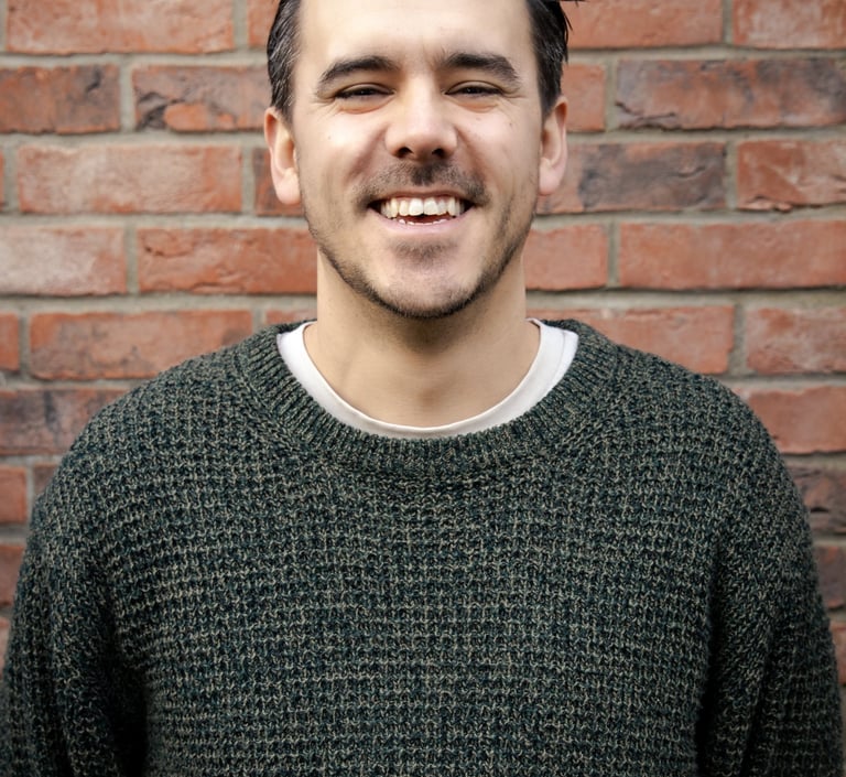 a man smiling in front of a brick wall background