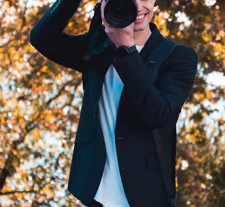 Fotograf Joel Pingel fotografiert lächelnd in herbstlicher Umgebung. Action-Portrait von Just Perspectives.