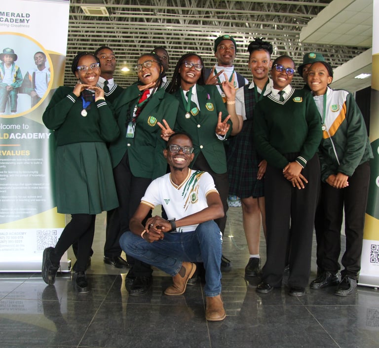 Happy Emerald Academy students in green school uniforms posing for a group photo at an indoor event.