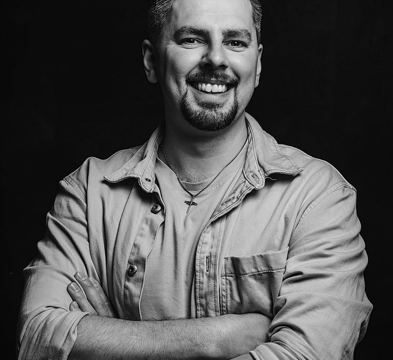 Albert Heit, lächelnd mit verschränkten Armen vor dunklem Hintergrund