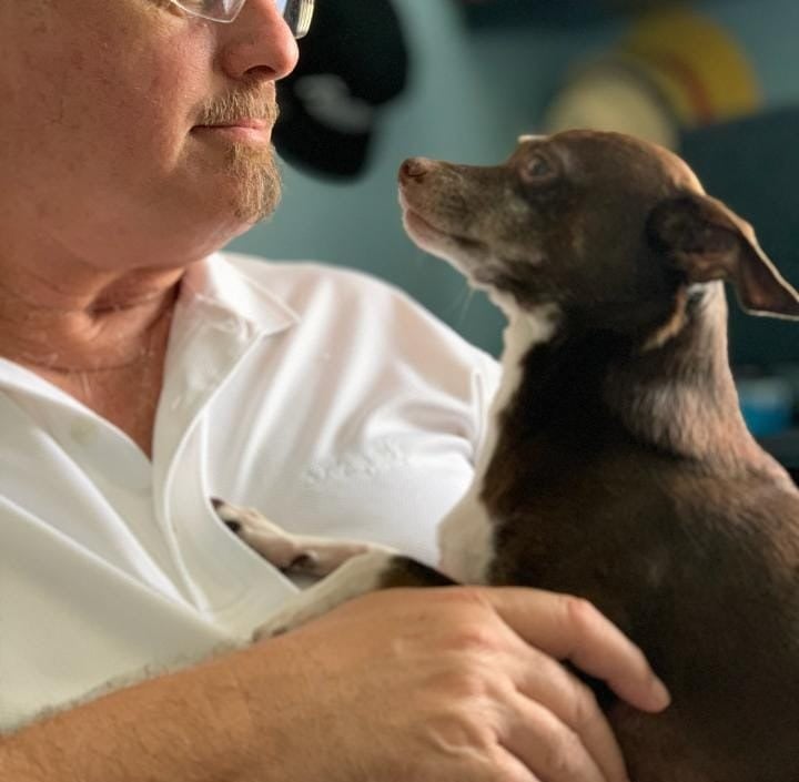 Robert in a white shirt is holding a dog during overnight boarding