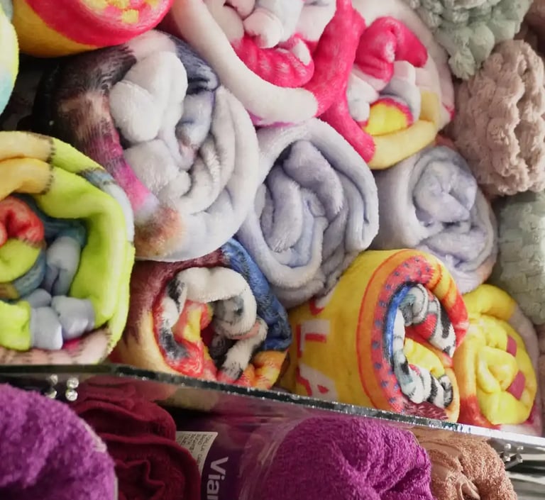 Una fila apilada de diferentes estilos de cobijas en la tienda.