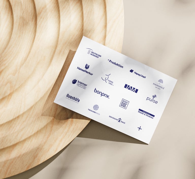 Flyer mit Logos von Kooperationspartnern liegt auf rundem Holztisch